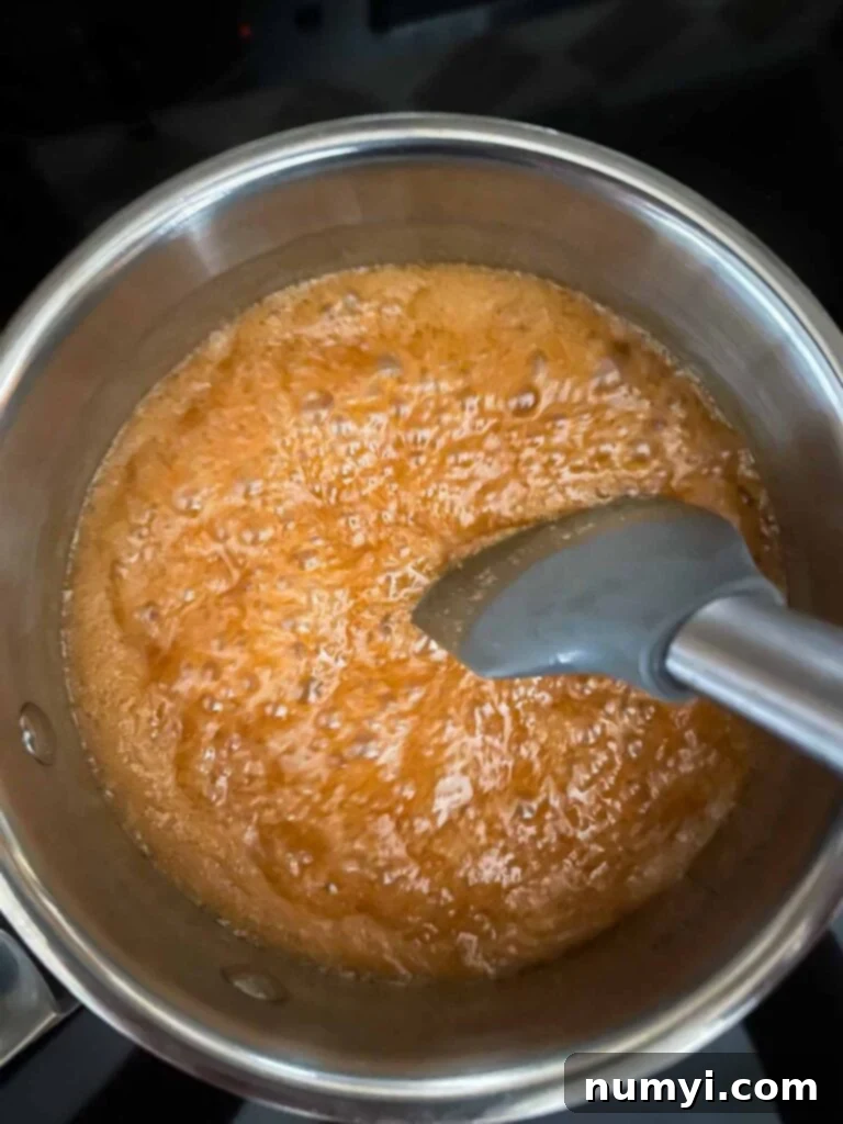 Salted Caramel Swirl Pumpkin Bread Pudding 10 Rich, bubbling salted caramel sauce simmering in a saucepan over medium heat, indicating it's reached the perfect stage of cooking.