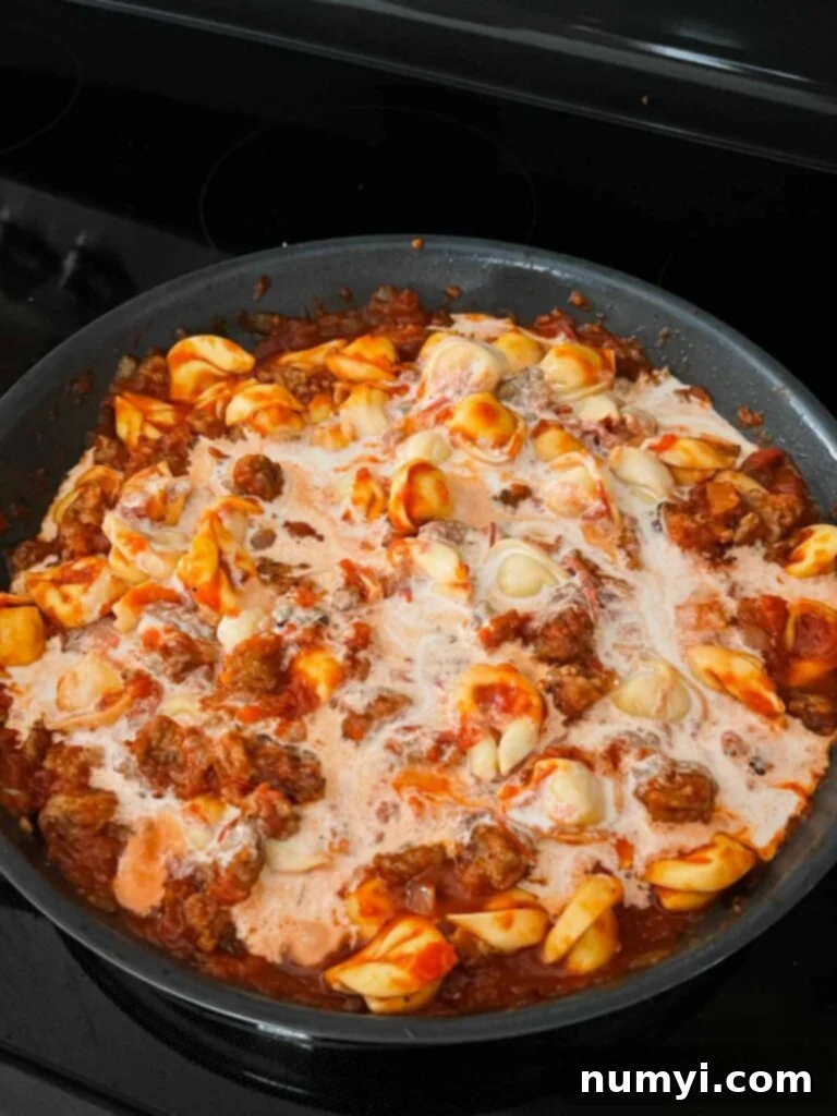 Cream added to a tortellini with italian sausage dish.