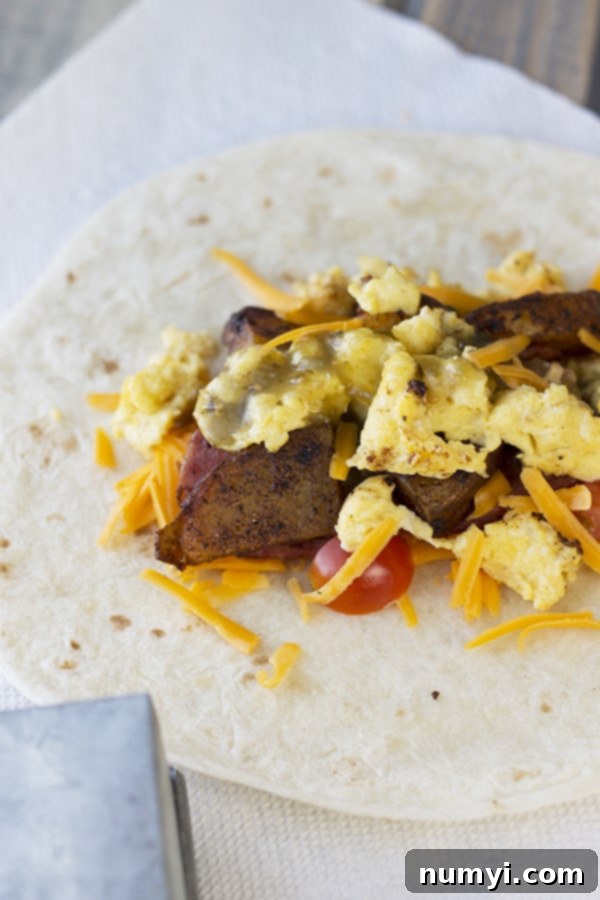 Grab-and-Go Breakfast Burritos 3 An open flour tortilla shell filled with perfectly scrambled eggs, shredded cheddar cheese, and crispy seasoned potatoes, ready for folding into a breakfast burrito.