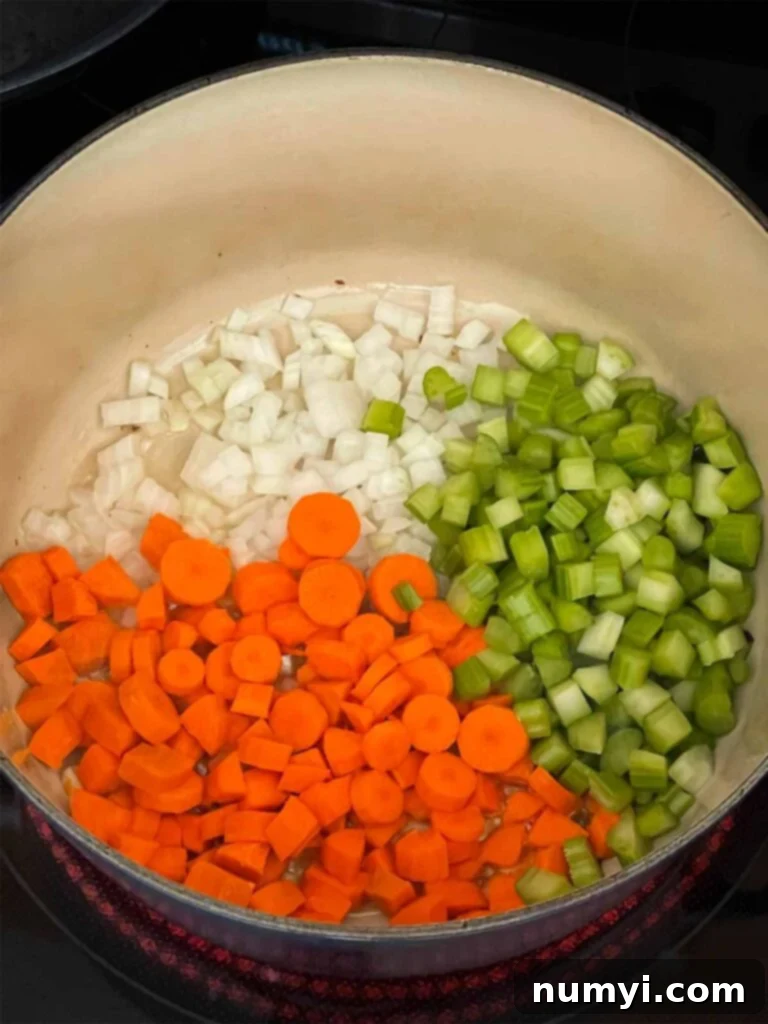 Velvety Potato Corn Chowder with Crispy Bacon 5 Onions, celery, and carrot just added to a dutch oven.