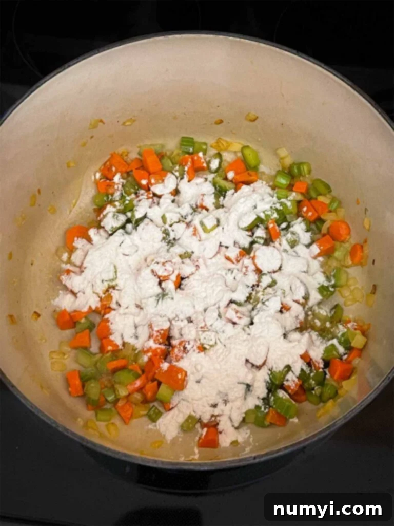 Velvety Potato Corn Chowder with Crispy Bacon 7 Flour being added to a mirepoix in a dutch oven.