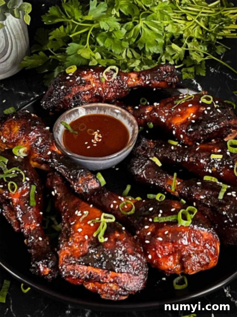 Gochujang chicken legs on a dark plate, beautifully smoked and basted.