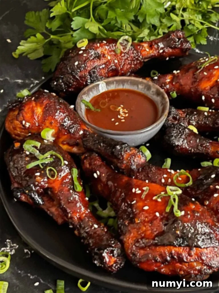 Smoked gochujang chicken legs on a dark plate, glazed to perfection.