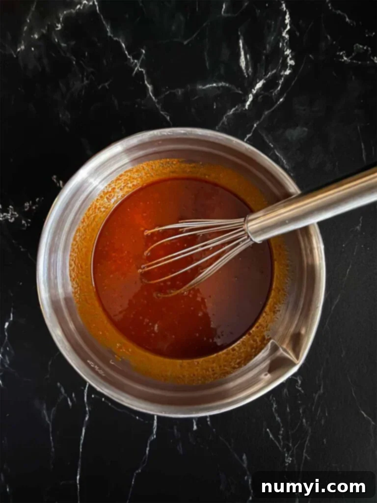 A rich, red gochujang marinade in a silver mixing bowl, ready for chicken.