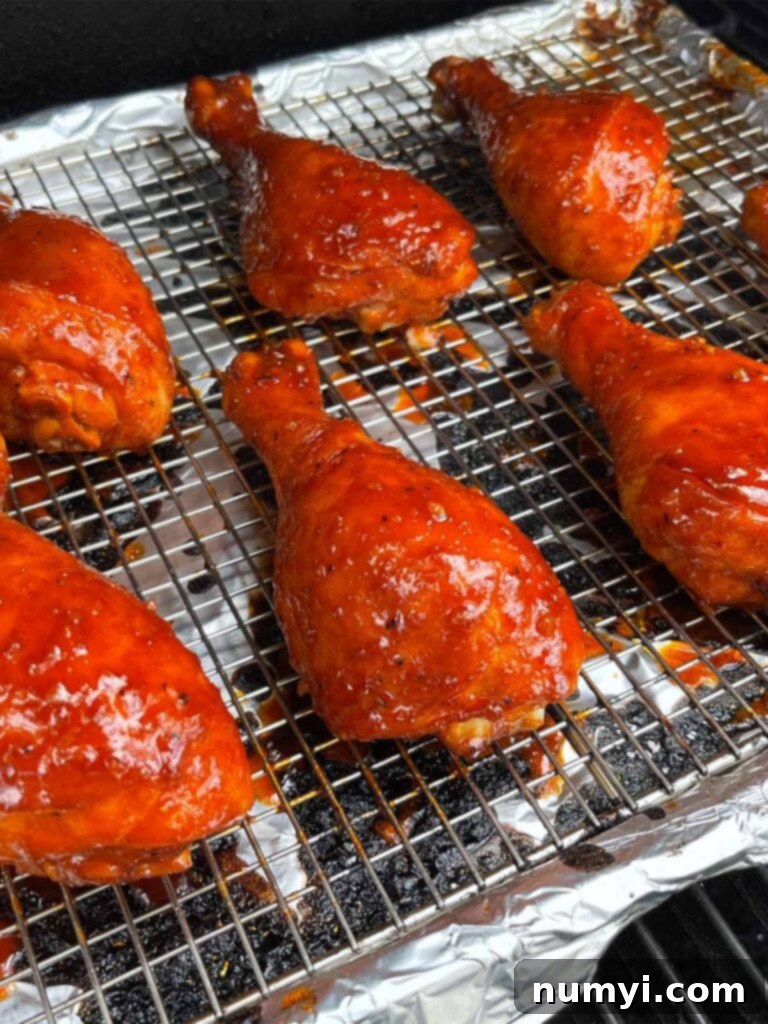 Chicken legs actively smoking on a grill, surrounded by aromatic wood smoke.