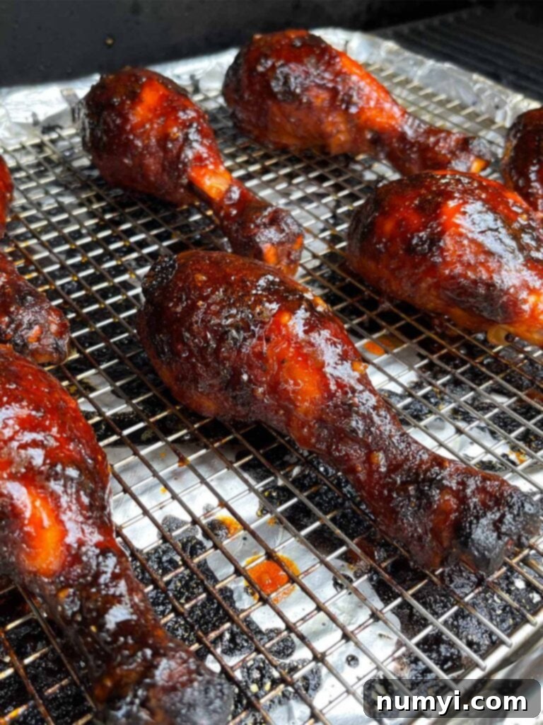 Gochujang chicken legs in the smoker, developing a rich, caramelized crust.