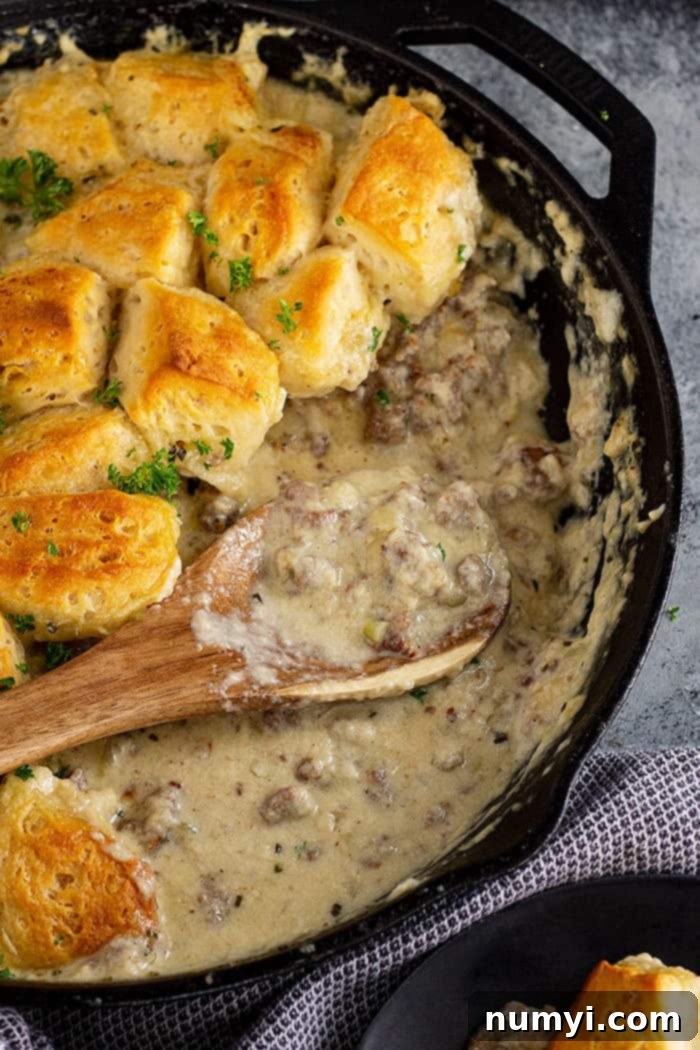 Close up of the creamy, savory gravy part of biscuit and gravy casserole, with bits of sausage visible.