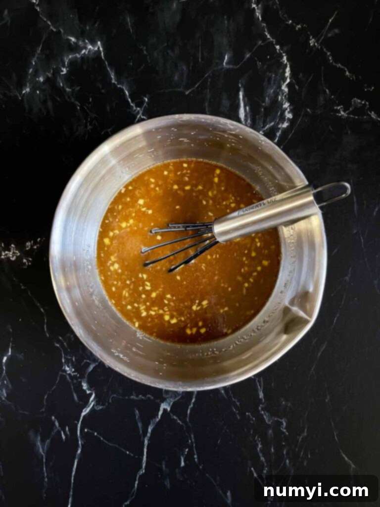 Chicken teriyaki marinade in an aluminium bowl on a dark surface.
