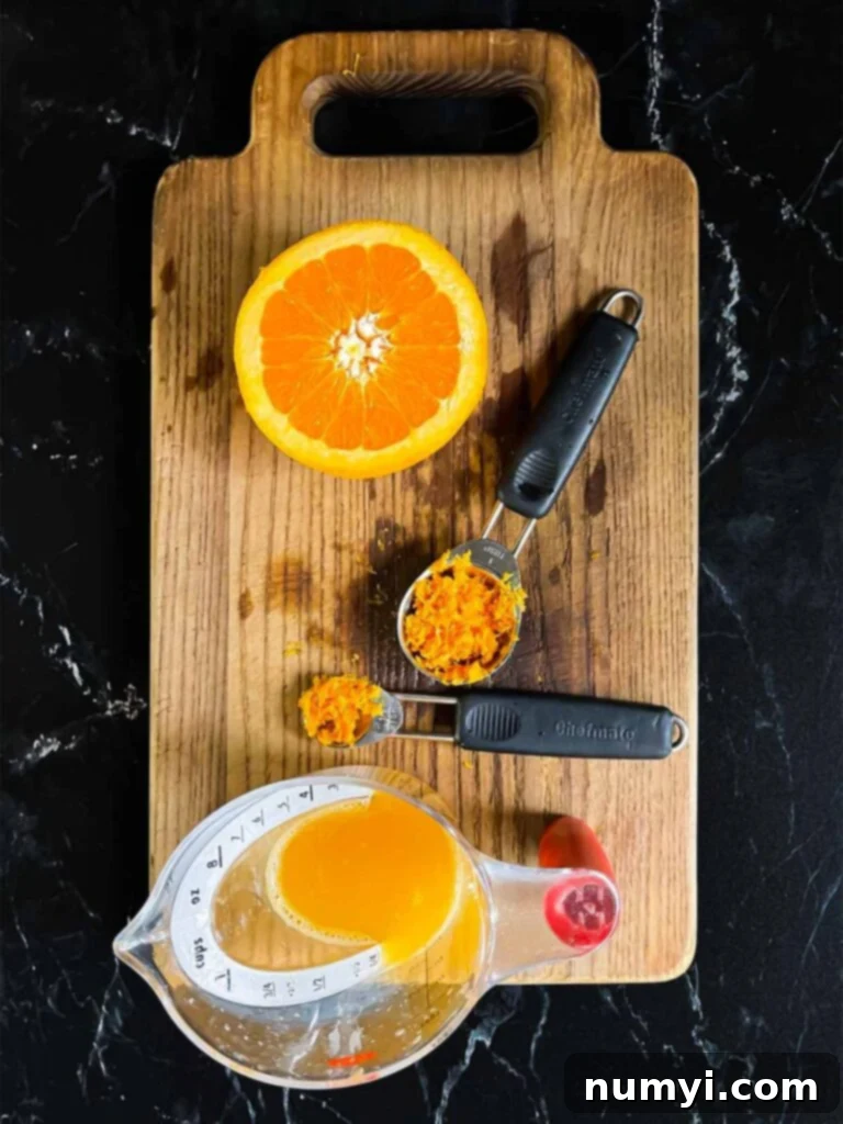 Zesty Cranberry Orange Loaf 4 Orange zest and fresh orange juice on a wooden cutting board.