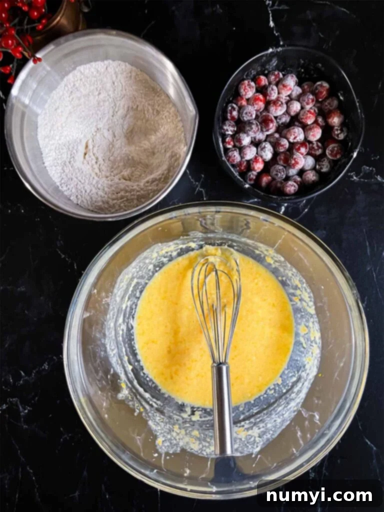 Zesty Cranberry Orange Loaf 6 Wet and dry ingredients for Cranberry Orange bread in various bowls on a dark surface.