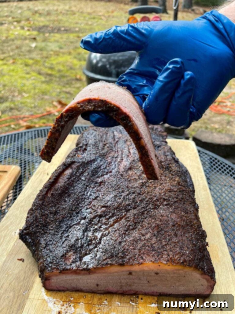 A slice of brisket from the flat being held by a couple of fingers.