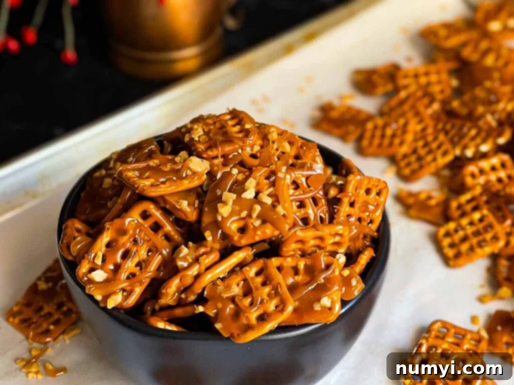 Butter toffee pretzels in a dark bowl on the baking sheet, showcasing their golden, crunchy coating.