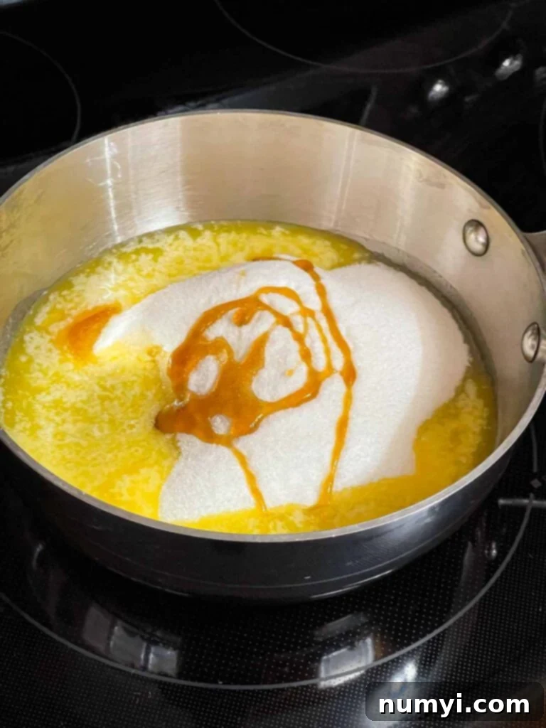 Butter, sugar, corn syrup, and water in a saucepan on a stove burner, ready to be cooked into toffee.