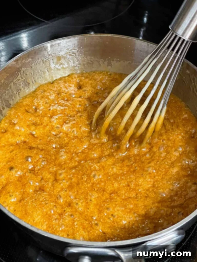 Close-up of the toffee mixture boiling vigorously in a metal saucepan, indicating it's reaching the hard crack stage.