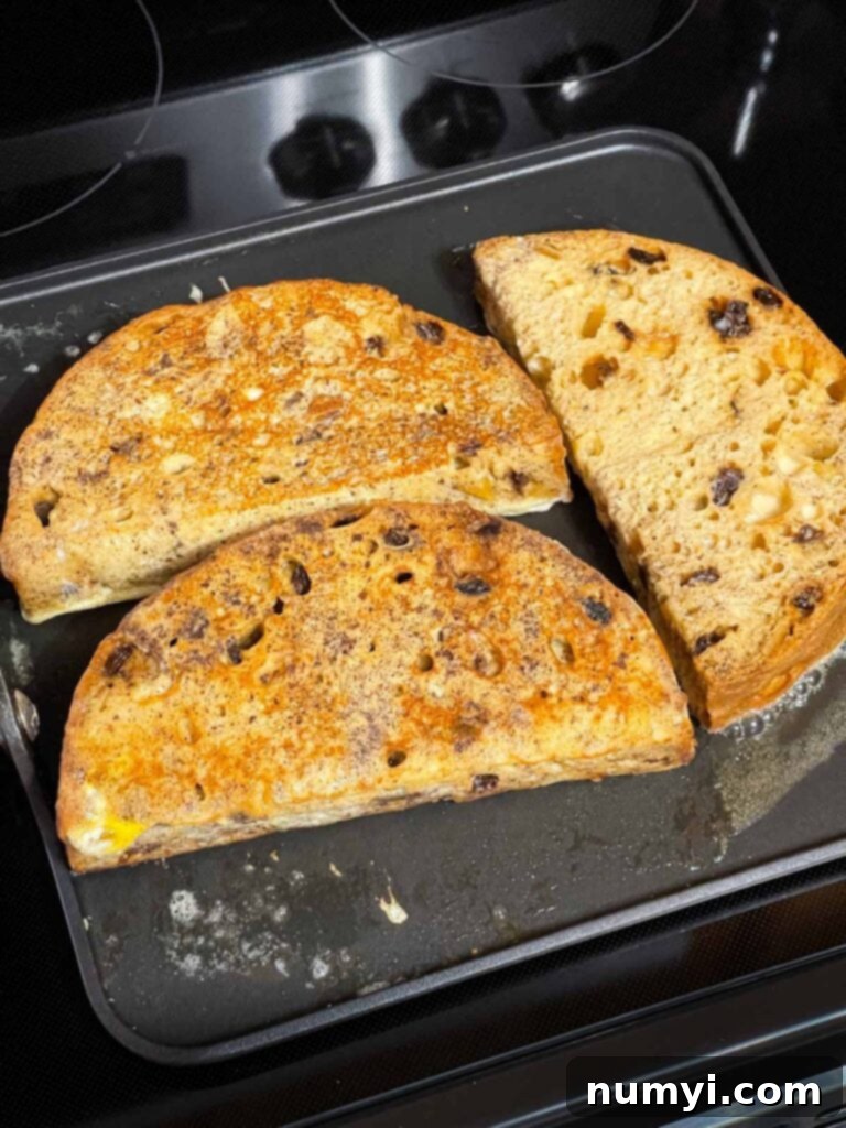 Slices of panettone french toast cooking on a buttered griddle.