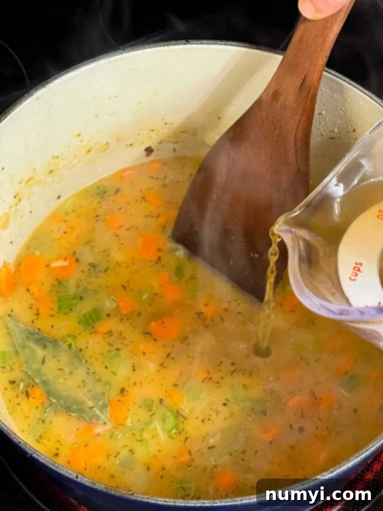 Adding chicken stock to a medley of vegetables in a dutch oven.
