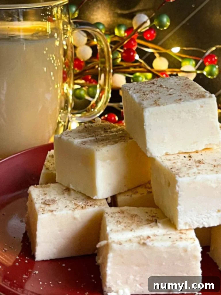 Eggnog fudge on a dark plate with a glass mug of eggnog.