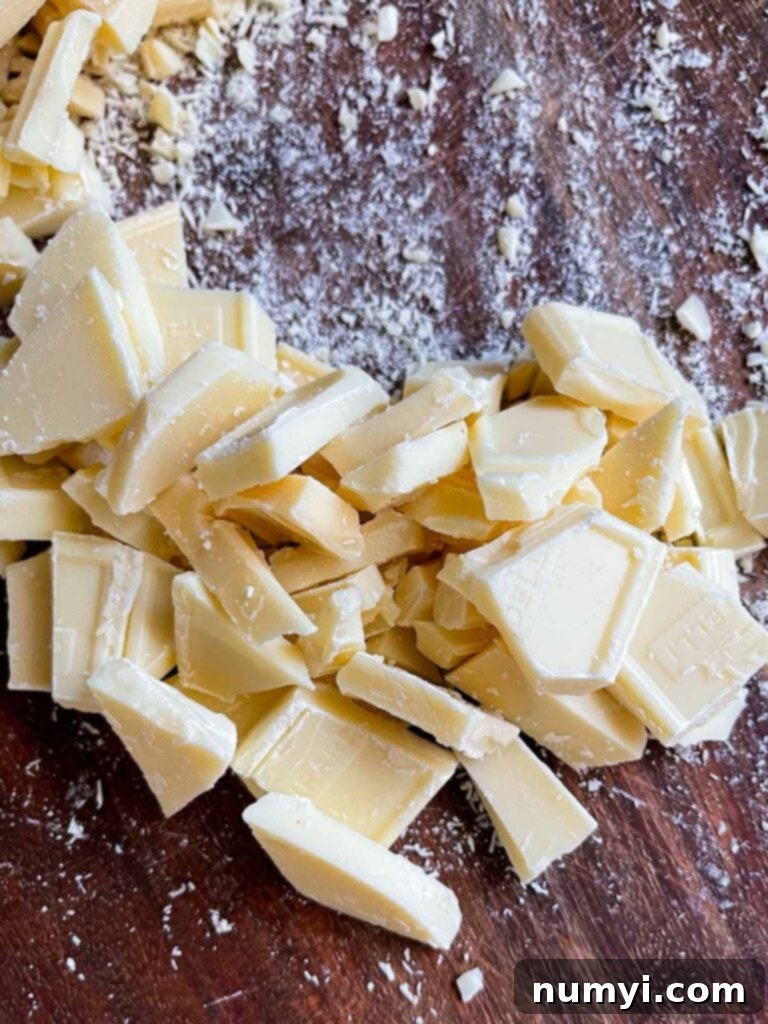 Chopped baking white chocolate bars on a wooden board.