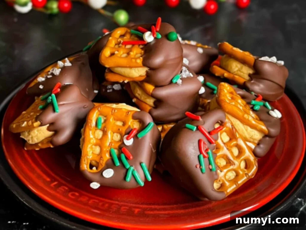 Chocolate covered peanut butter pretzel bites stacked on a dark plate.