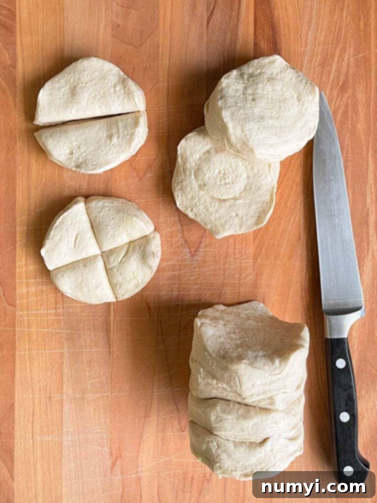 Fluffy Biscuit Pigs 5 Refrigerated biscuit dough cut into quarters on a wooden board.