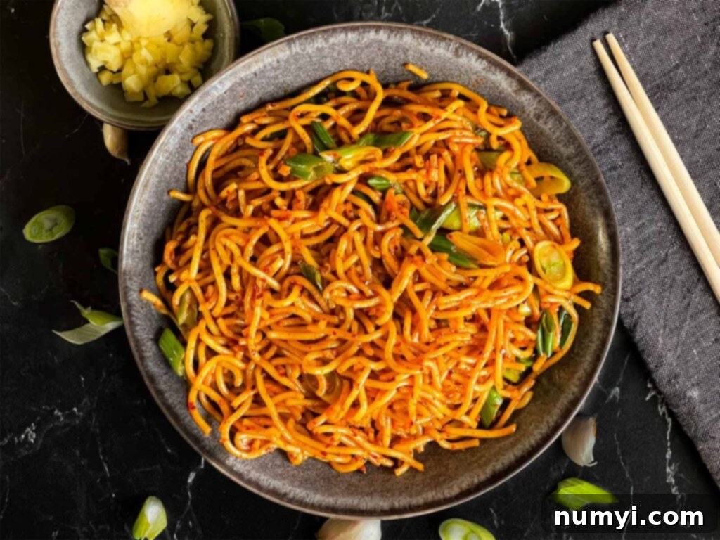 Fiery Garlic Noodle Express 2 Spicy garlic noodles in a dark bowl, garnished with green onions and chili flakes.