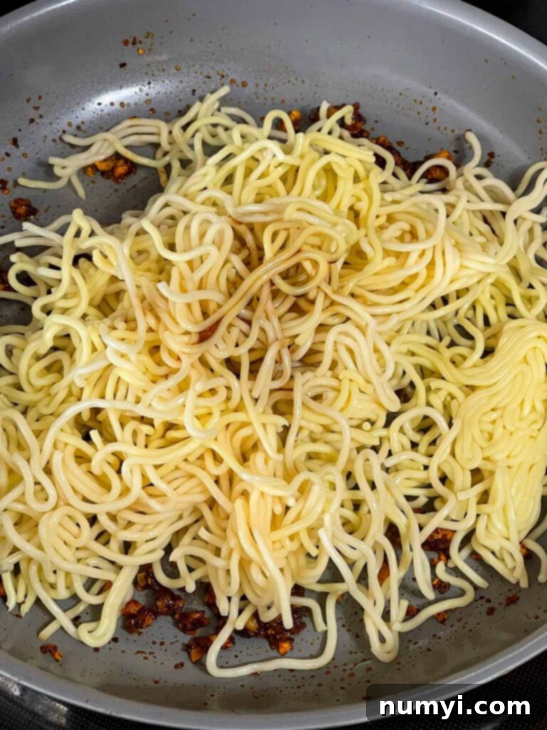 Fiery Garlic Noodle Express 8 Cooked stir-fry noodles added to the skillet with sauce.