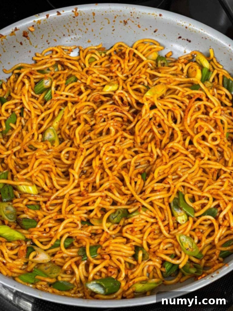 Fiery Garlic Noodle Express 10 Spicy garlic noodles, thoroughly mixed with green onions, in a skillet.