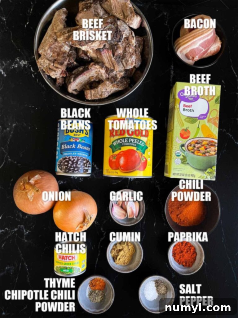 A collection of fresh and canned ingredients, including diced white onions, garlic cloves, various spices, a can of whole tomatoes, and sliced bacon, all neatly arranged on a wooden board, ready for making brisket chili.