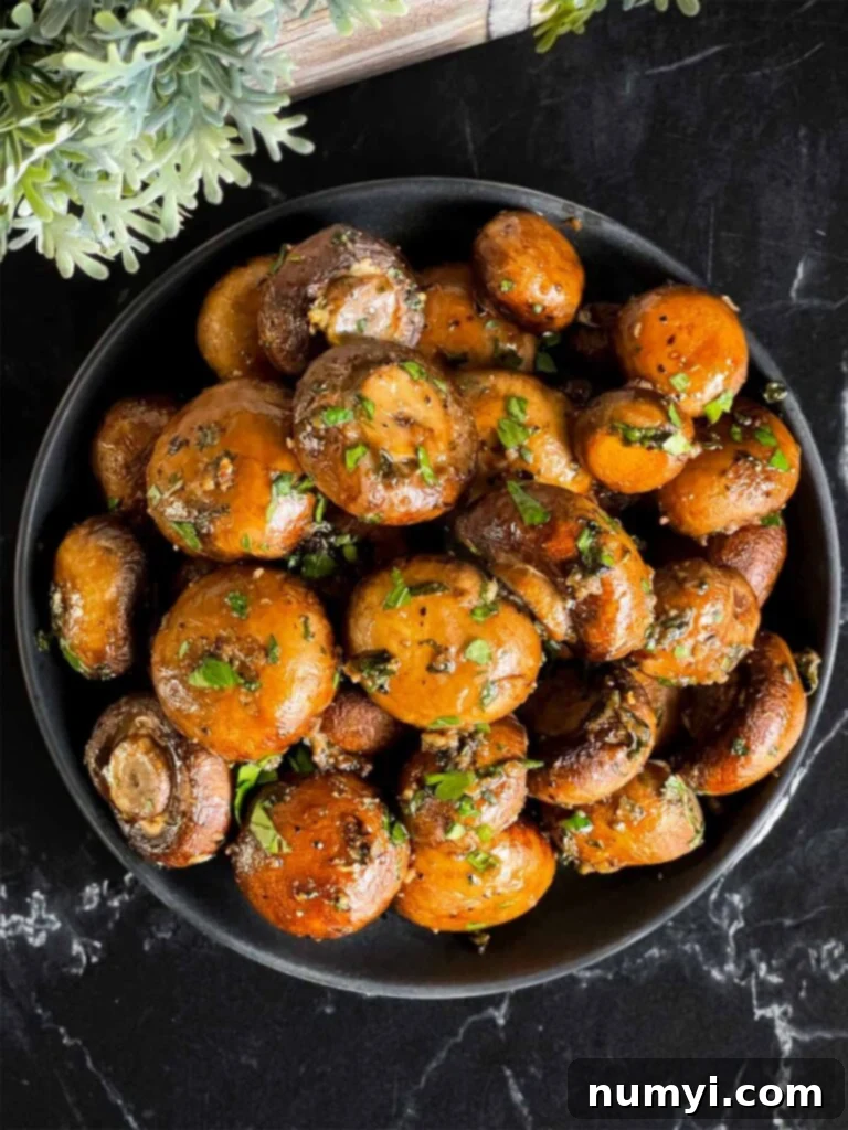 Garlic butter roasted mushrooms served in a dark ceramic bowl, ready to be enjoyed as a side dish.