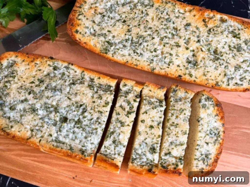 Perfectly golden-brown homemade garlic bread slices arranged on a rustic wooden cutting board, ready to serve.