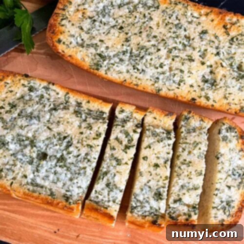 Perfectly golden-brown homemade garlic bread slices arranged on a rustic wooden cutting board, ready to serve.