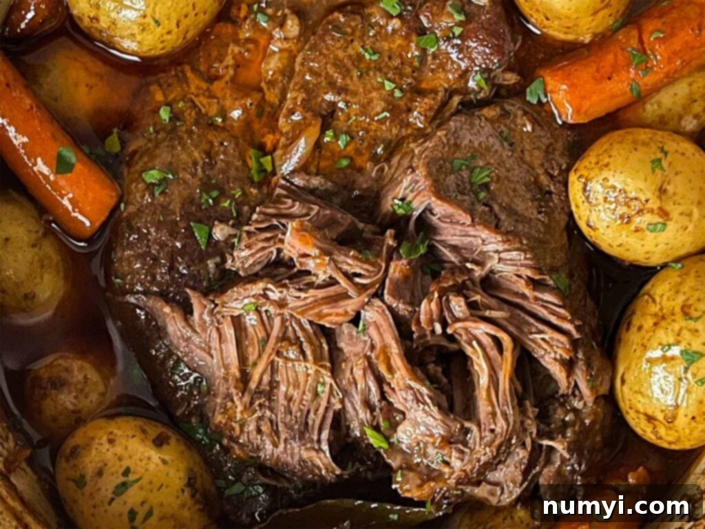 Grandma's Hearty Pot Roast 2 Classic pot roast with potatoes and carrots in a dutch oven on a dark surface.