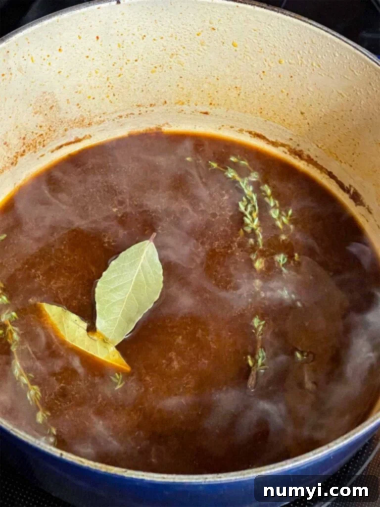 Grandma's Hearty Pot Roast 6 Beef broth, bay leaves, and fresh thyme added to a dutch oven for the pot roast recipe.