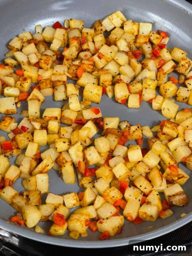 Hearty Smoked Pulled Pork Hash 7 Potatoes, onion, and red bell pepper cooking in a skillet.