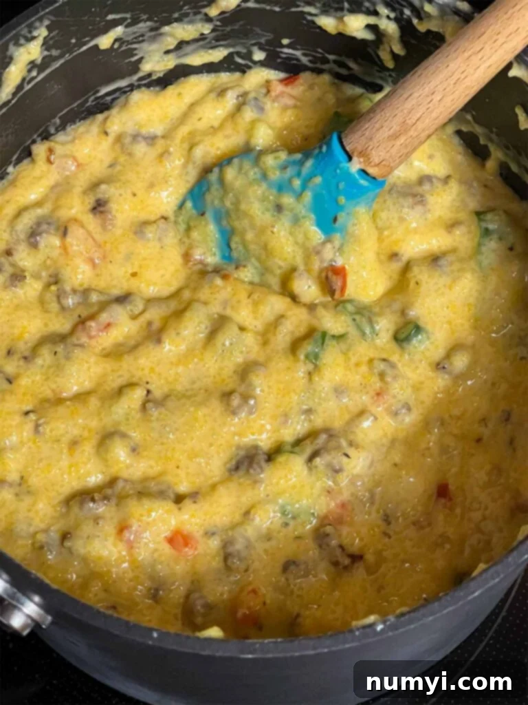 Cheesy Sausage Grits Bake 11 Grits with sausage and other herbs and spices in a saucepan.