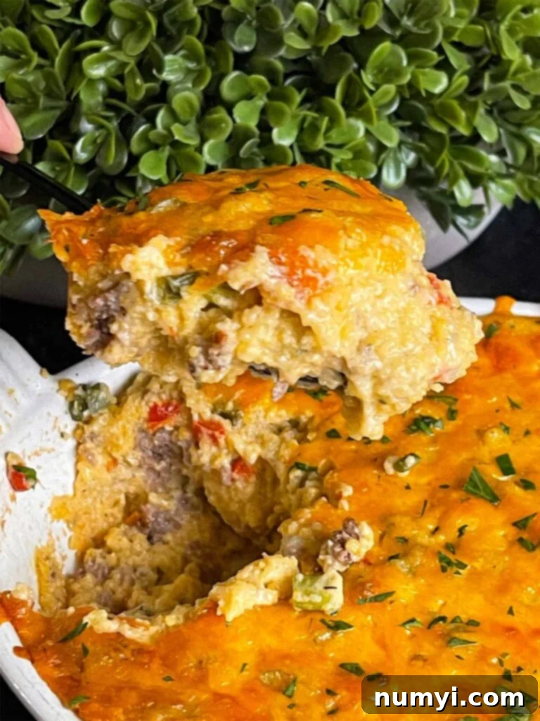 Cheesy Sausage Grits Bake 14 Baked sausage and cheese grits in a casserole dish with a serving resting on a spatula.