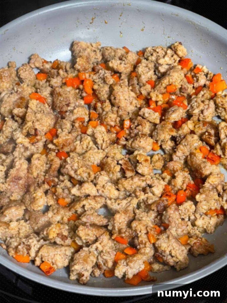 Cheesy Sausage Grits Bake 5 Browned sausage with diced red bell pepper in a skillet.