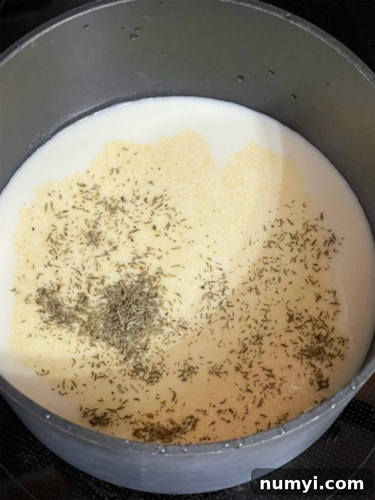 Cheesy Sausage Grits Bake 7 Milk with seasonings in a saucepan.