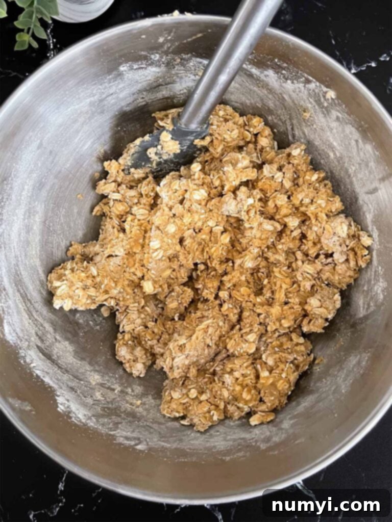 Oatmeal cookie dough for oatmeal fudge bars mixed in a metal mixing bowl.