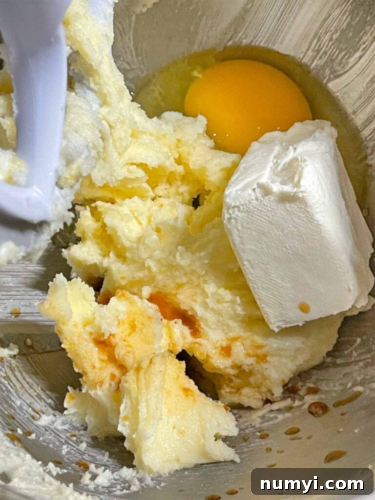 Cream cheese, egg, and vanilla extract added to the creamed ingredients for lemon thumbprint cookies.