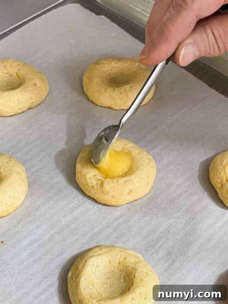 Lemon curb being placed in the thumbprint of the cookies.