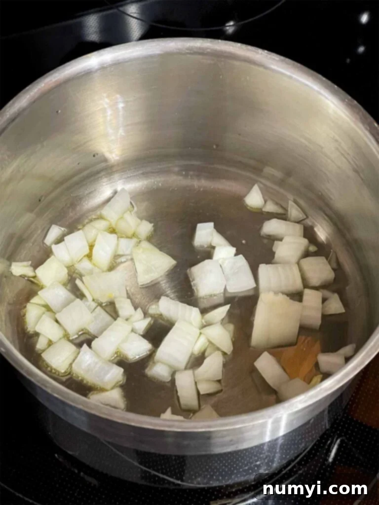 Diced onions cooking in olive oil in a pot.