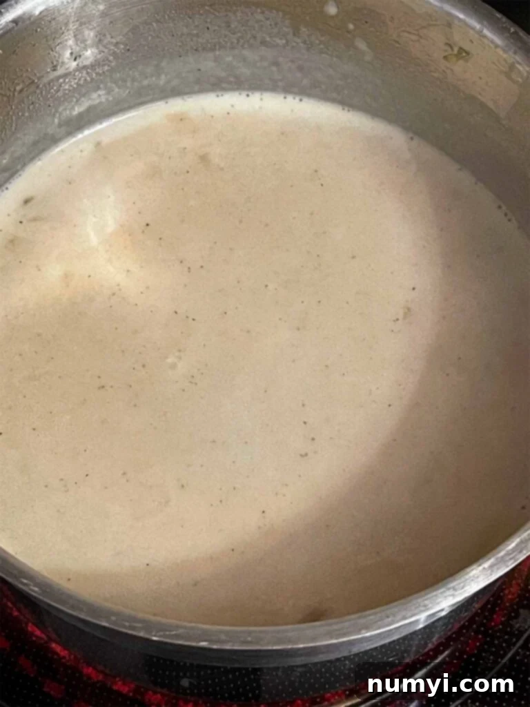 A creamy Tetrazzini sauce cooking in a pot, thickening to perfection.
