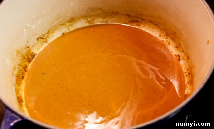 A perfectly cooked dark roux, rich and amber-brown, bubbling gently in a Dutch oven.
