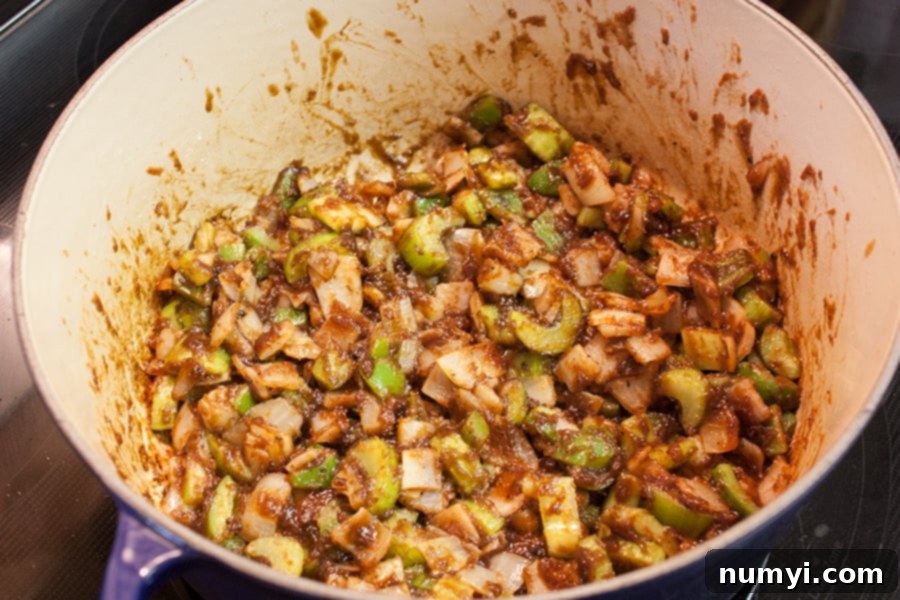 The holy trinity of onions, bell peppers, and celery cooking down in the rich, dark roux, releasing their aromas.