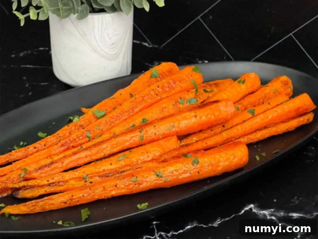 Sweet & Savory Roasted Whole Carrots 2 Roasted whole carrots on a dark plate garnished with chopped parsley.