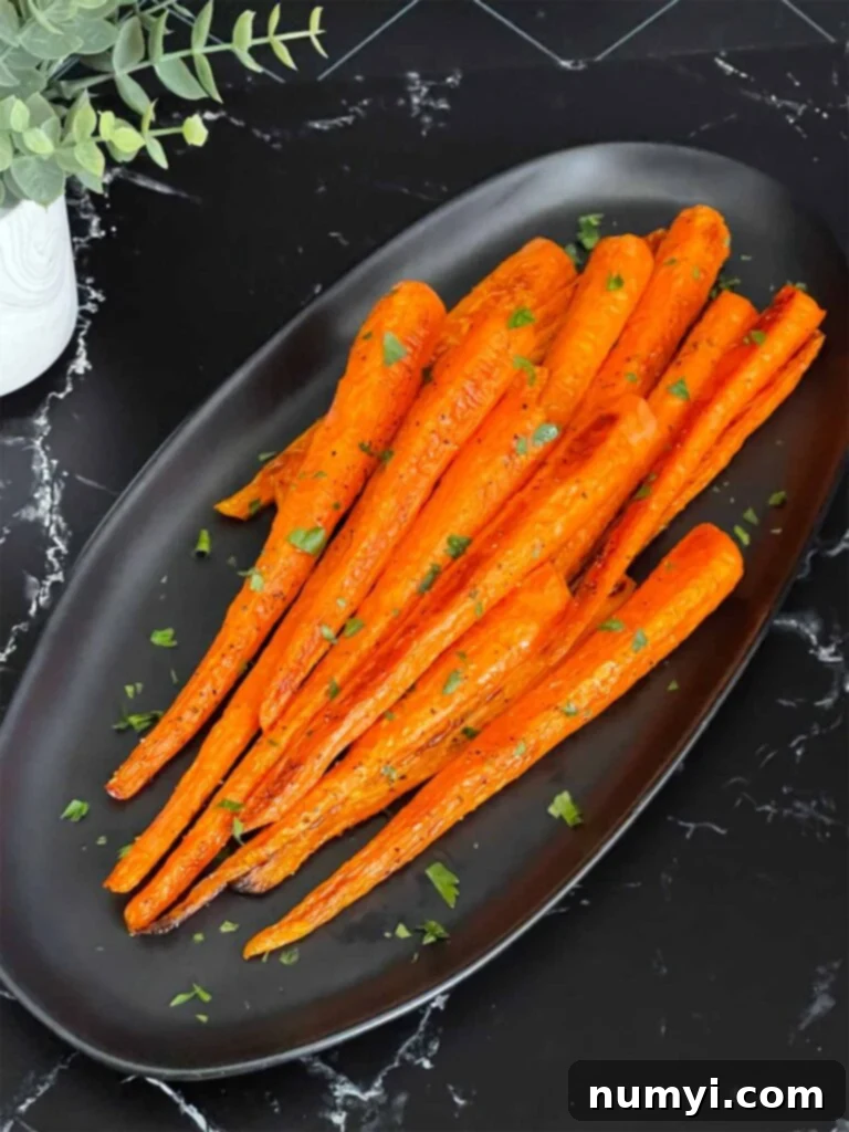 Sweet & Savory Roasted Whole Carrots 5 Roasted whole carrots on a dark plate garnished with chopped parsley.