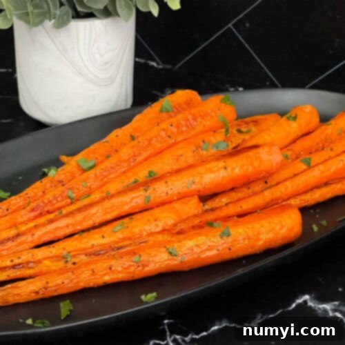 Sweet & Savory Roasted Whole Carrots 6 Roasted whole carrots on a dark plate garnished with chopped parsley.