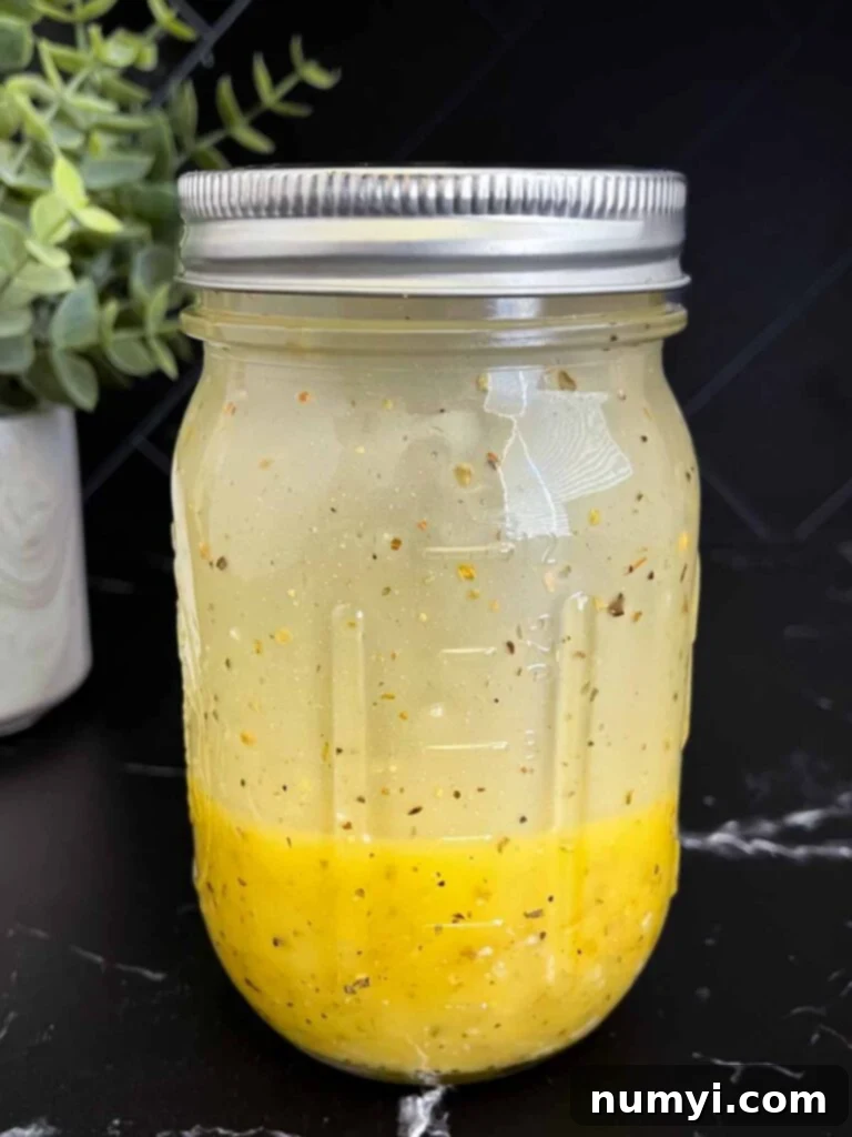 Marinated cauliflower salad dressing mixed in a mason jar on a dark surface.