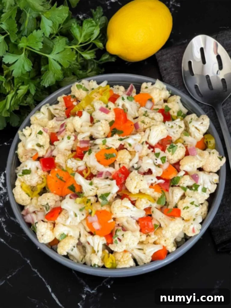 Marinated cauliflower salad in a dark bowl on a dark surface.
